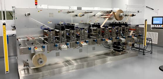 Industrial machine with multiple rollers and control panels in a clean room.