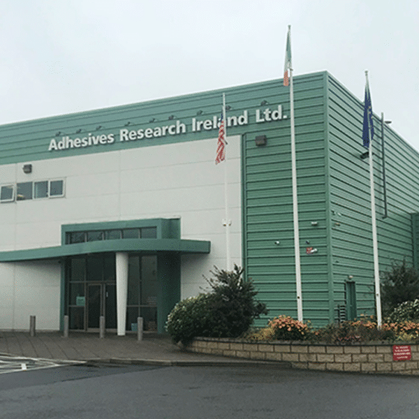 Exterior of Adhesives Research Ireland Ltd. building with flags.