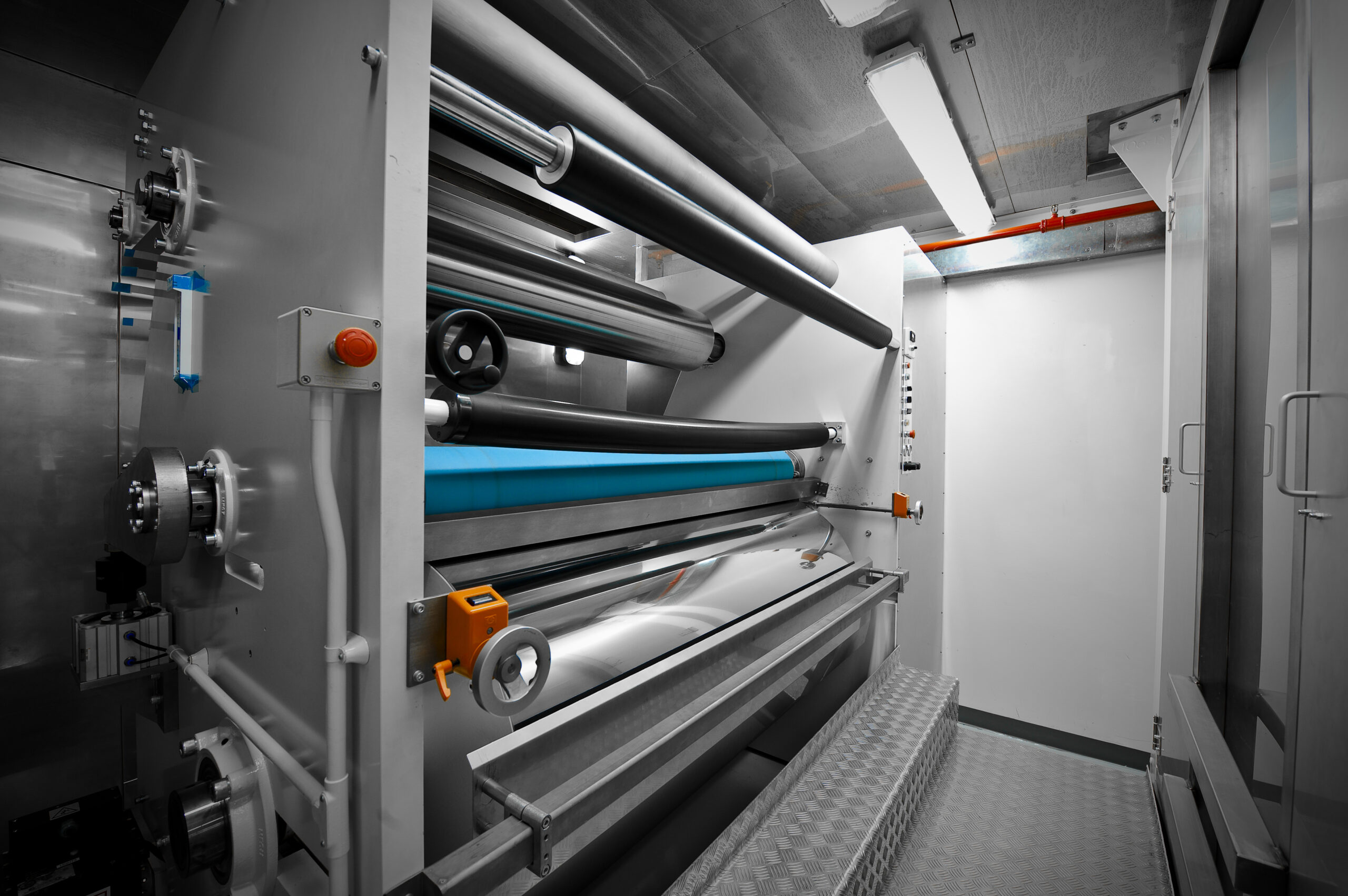 A large industrial laminating or rolling machine from Adhesives Research, featuring multiple metal rollers and control panels in a clean, modern facility.