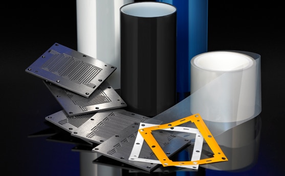 Various industrial films and plates displayed on a dark surface.