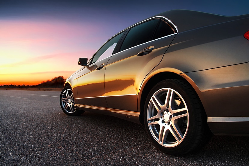 Luxury car parked on a road at sunset