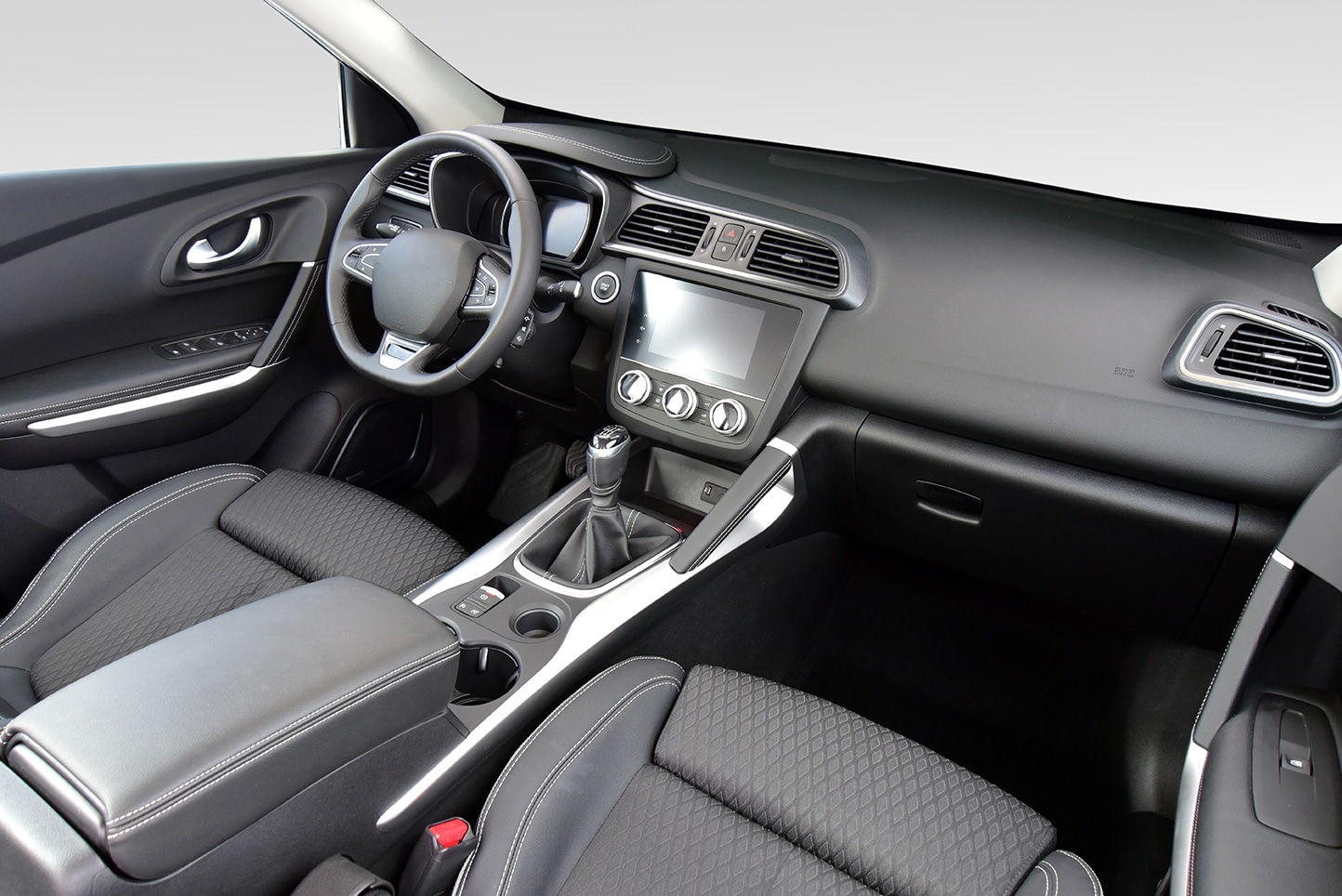 Interior view of a modern car with dark upholstery, a steering wheel, and a touchscreen display.